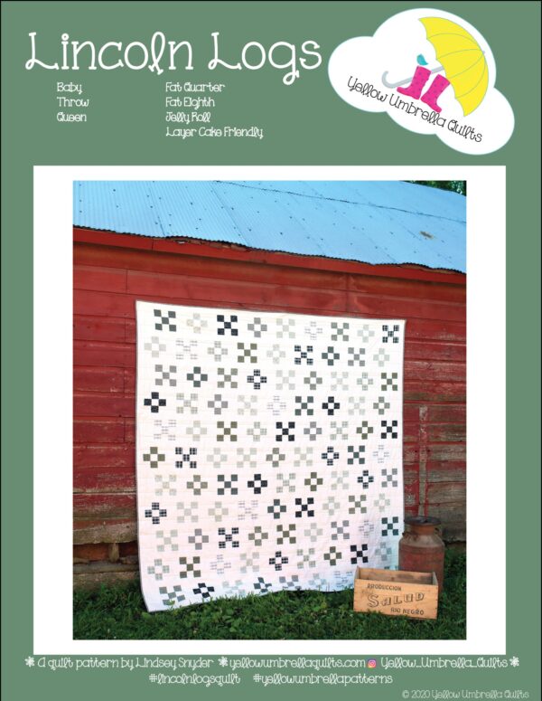 A Lincoln Logs quilt from Yellow Umbrella Quilts hanging on the side of a barn.